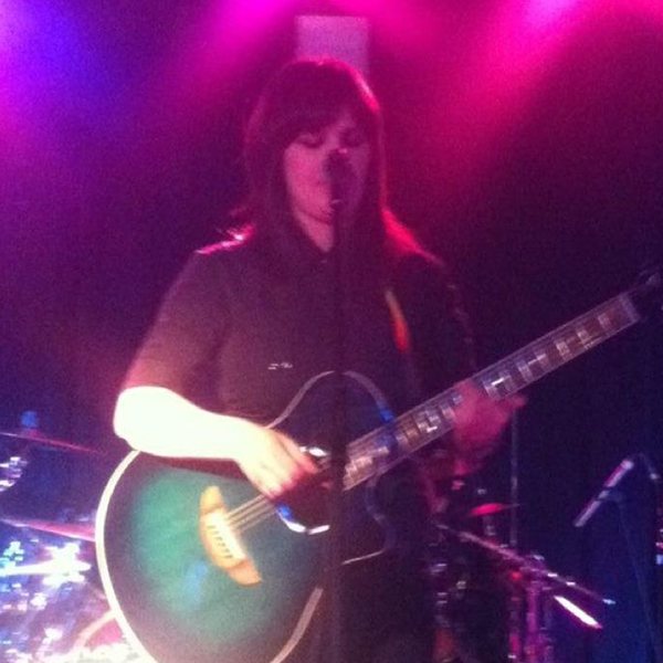 Cat singing with her acoustic guitar under pink stage lights