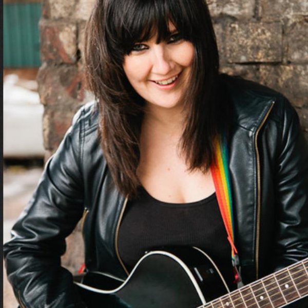 Cat with her guitar against a brick wall