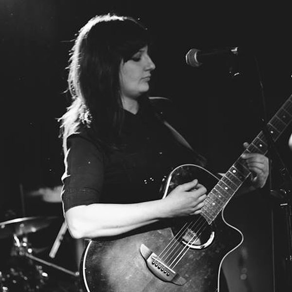 Cat playing acoustic guitar on stage